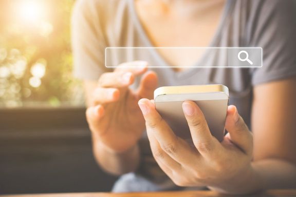 女性はスマートフォンを使って興味を持っているものを見つけます。インターネットネットワークの概念に関する情報データの検索