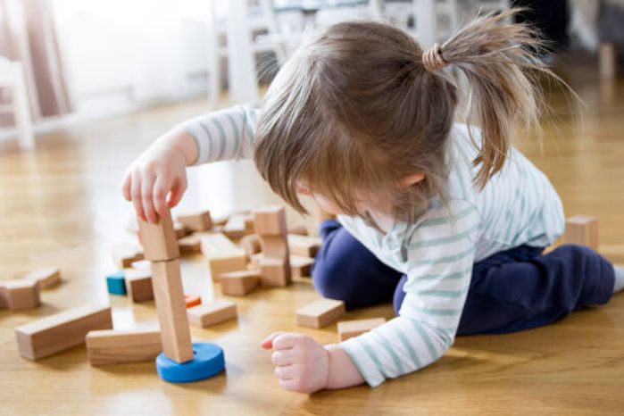 2 年古い女の子は再生され、木のおもちゃブロックの塔を構築