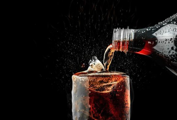 暗い背景に氷スプラッシュとガラスに清涼飲料を注ぐ。