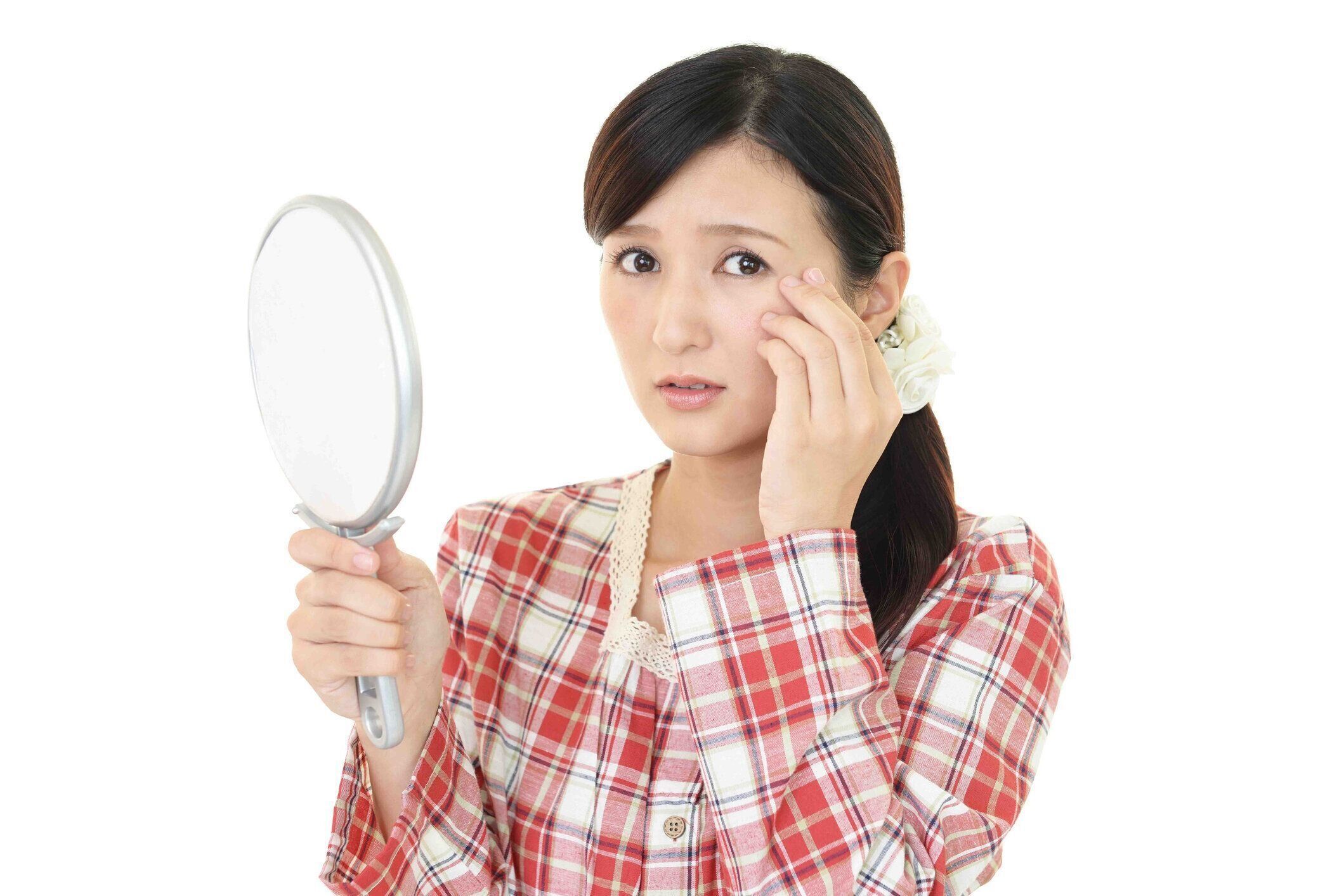 心配な表情でスキンケアをしている女性