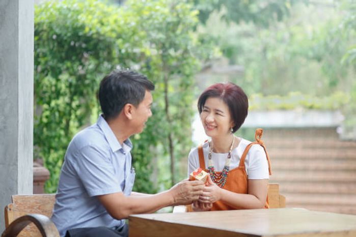 アジアの中年の男性は結婚記念日に彼の妻にプレゼントを与えます
