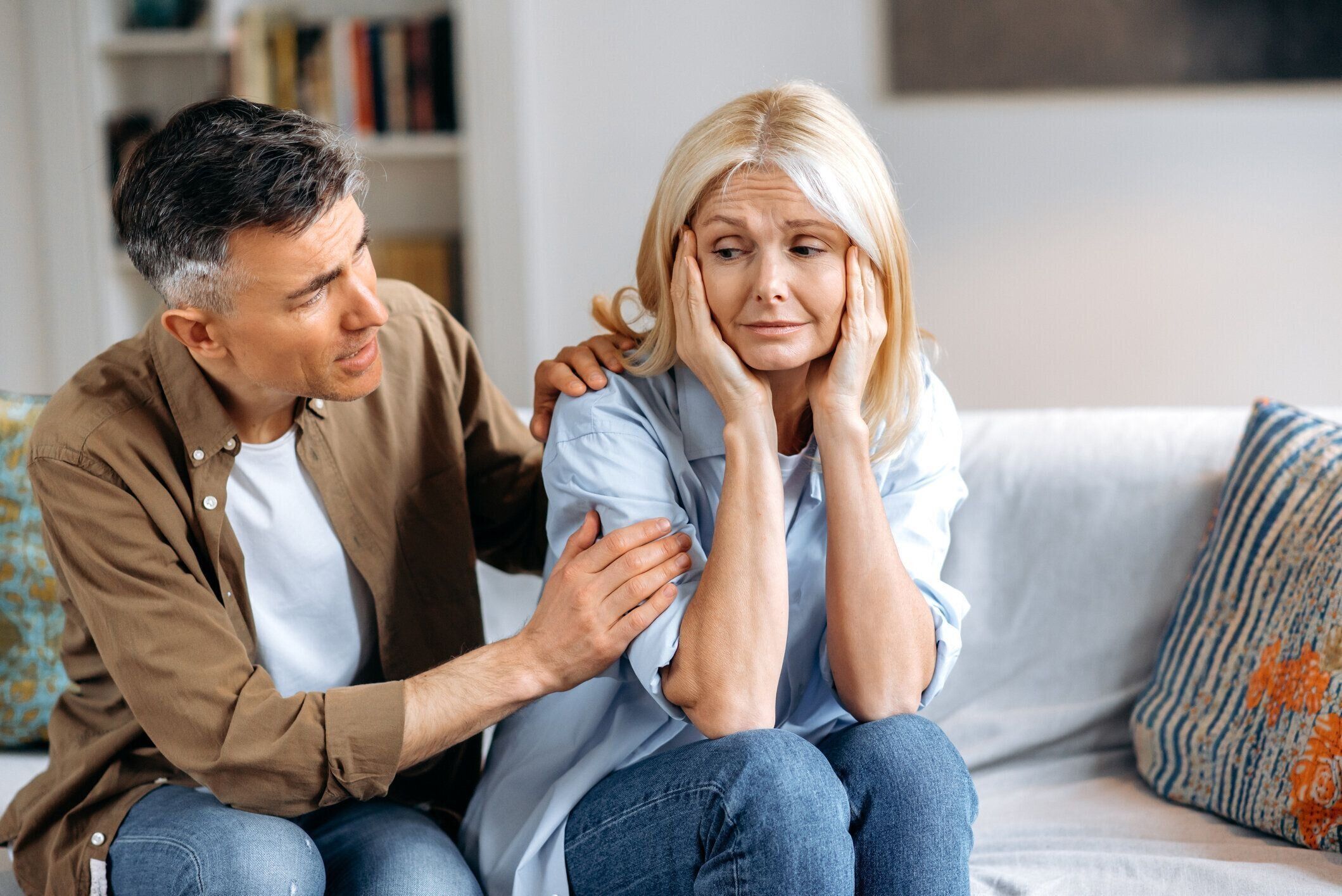 家庭での中年夫婦の対話。思いやりのある成熟した夫は、喧嘩の後に妻を落ち着かせ、妥協し、許しを求め、肩をなでる