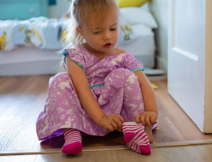 服を着る方法を学ぶ幼児は、外出するために彼女の靴下を履きます。子どもの発達。