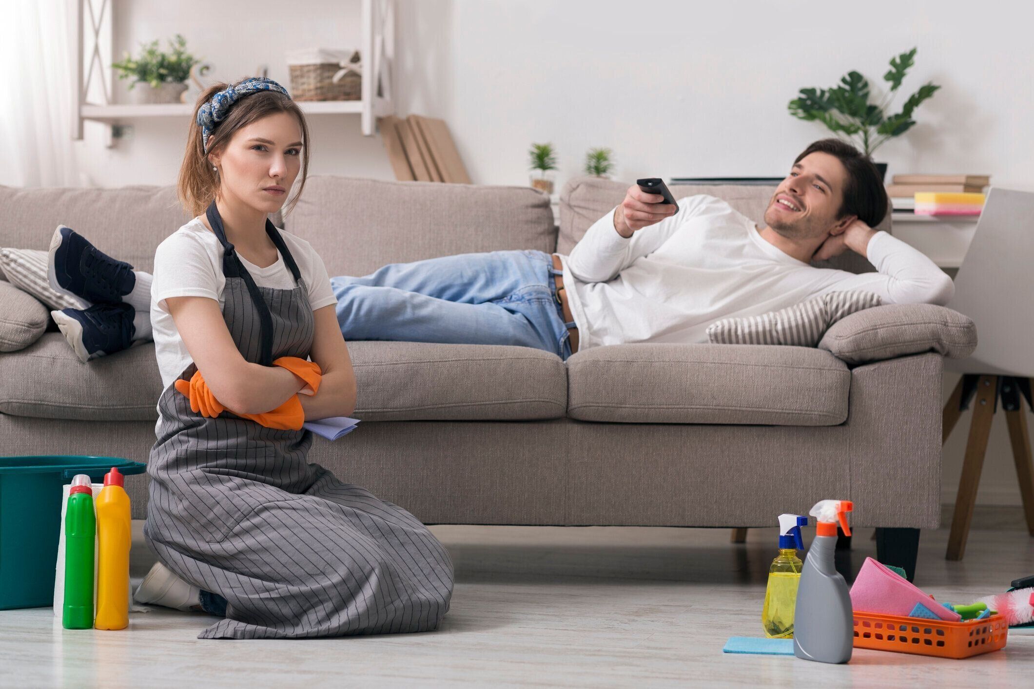 家事。怠惰な夫の隣に座って掃除した後に疲れた気分の女性