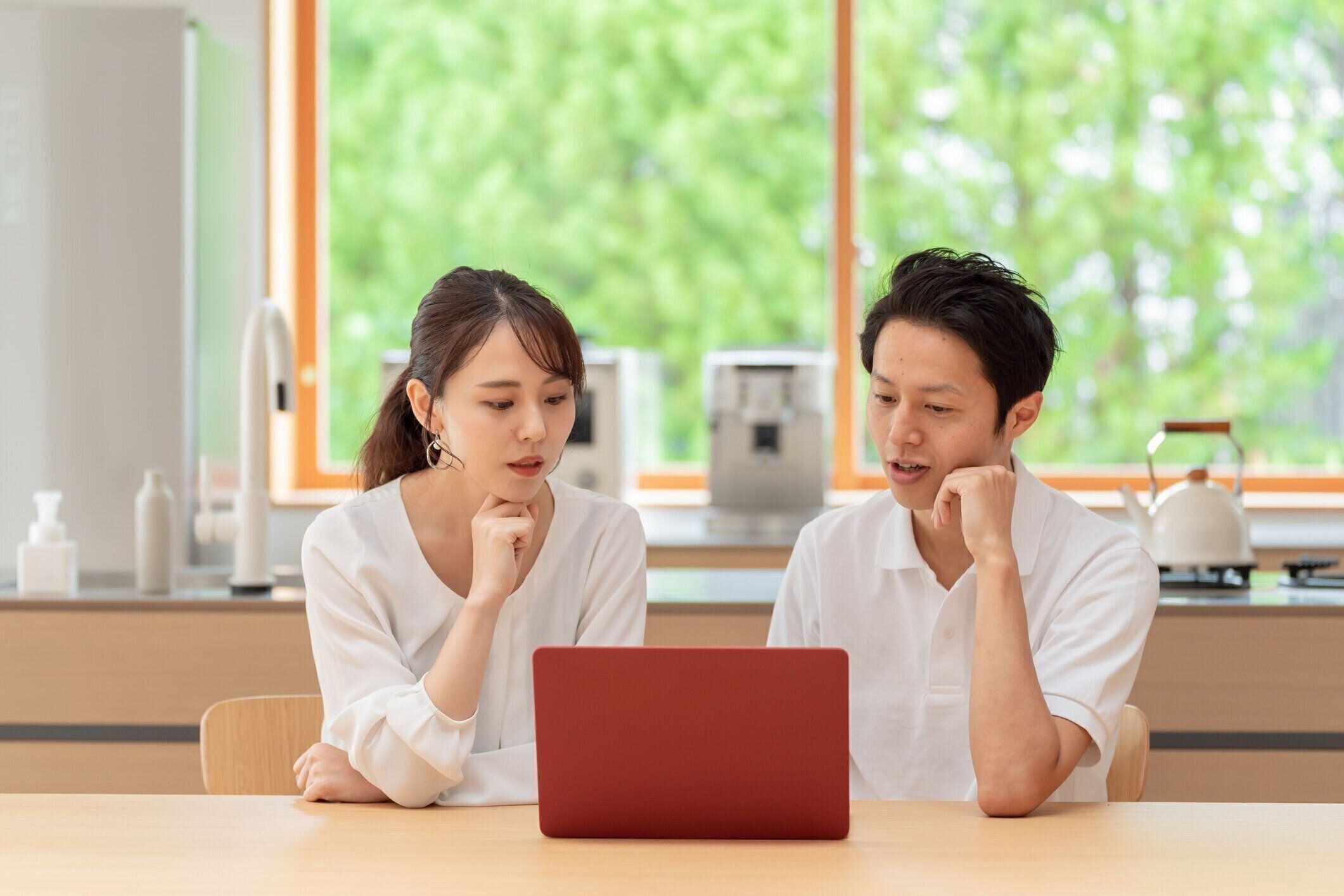 台所でラップトップを使用して若い日本のカップル