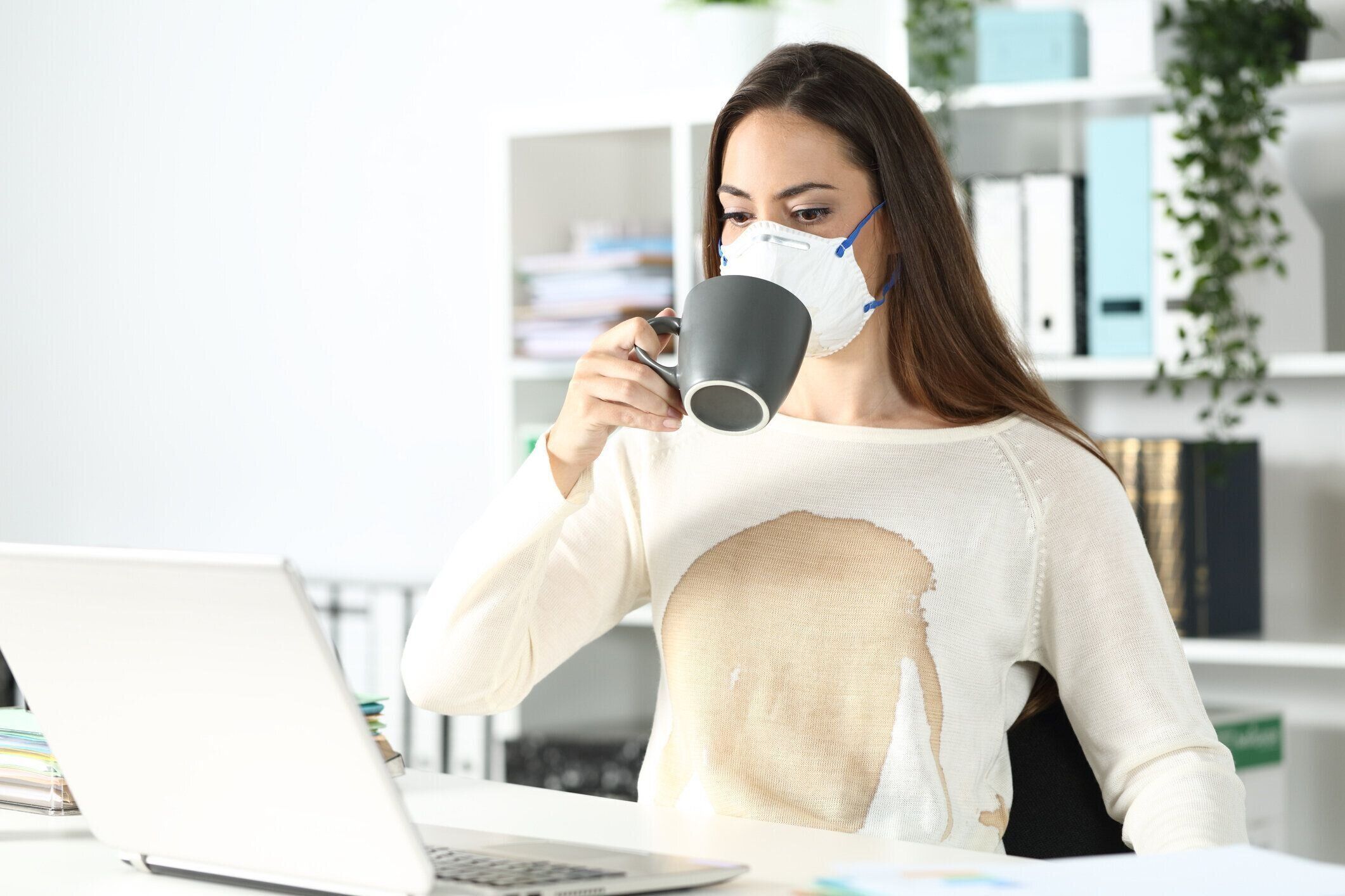 シャツの上にこぼれたコーヒーとマスクを身に着けている起業家