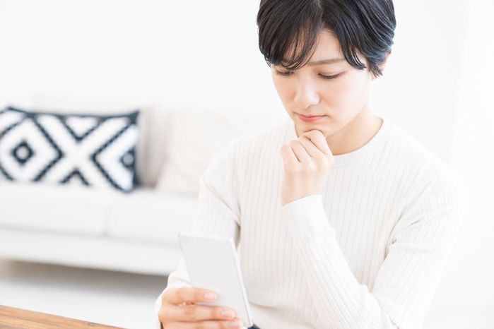 スマート フォンを見て魅力的なアジアの女性、考える、