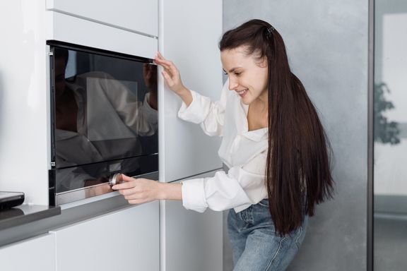 電子レンジノブを回す笑顔の若い女性
