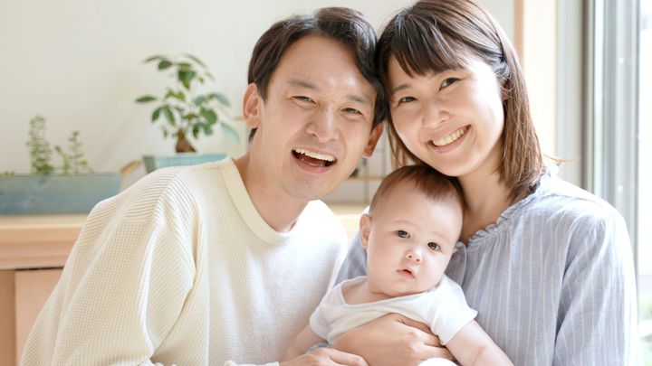 リビングルームに赤ちゃんがいる若い家族の肖像画