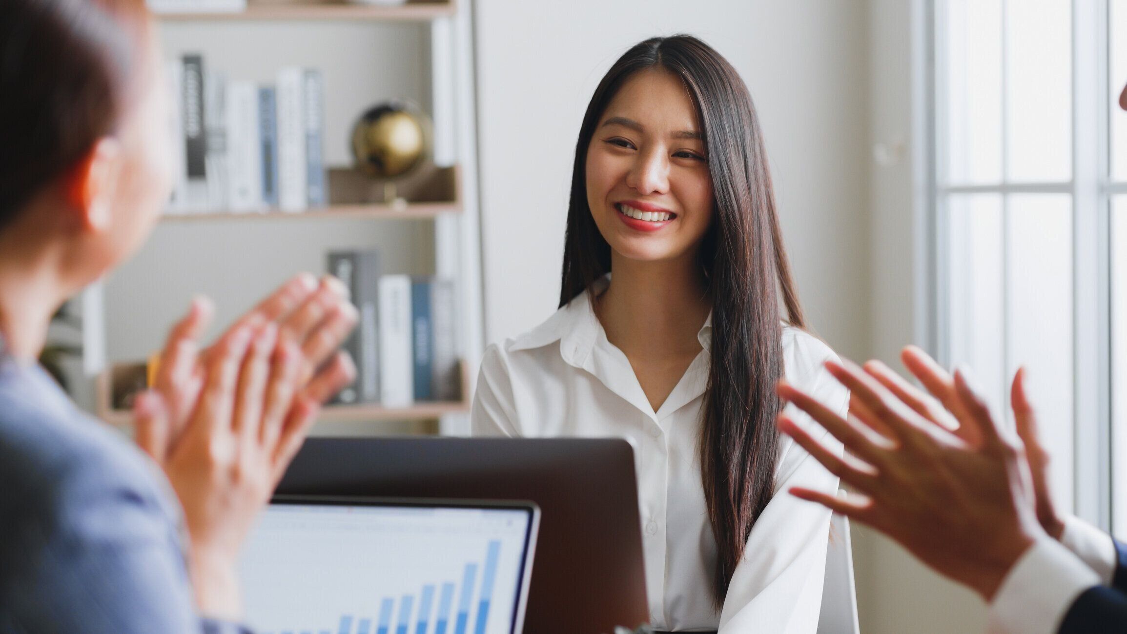 ビジネスチームは、ビジネス成果、仕事の昇進、ビジネスチームの拍手と歓声でアジアの若い女性の同僚とお祝いします。