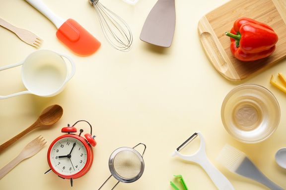 ベージュの背景に野菜を持つ様々なキッチン用品、上の景色、テキストのための場所。