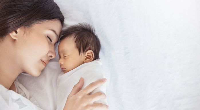 コピースペースでベッドで彼女の健康な新生児の睡眠にキス美しい若いアジアや白人の母の女の子の肖像画をクローズアップ。ヘルスケアと医療愛 アジア女性ライフスタイル母の日の概念