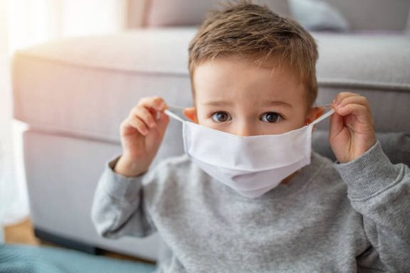 自宅に滞在アンチウイルスマスクを身に着けている小さな男の子。