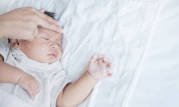 母親が病気の赤ちゃんの温度をチェックします。