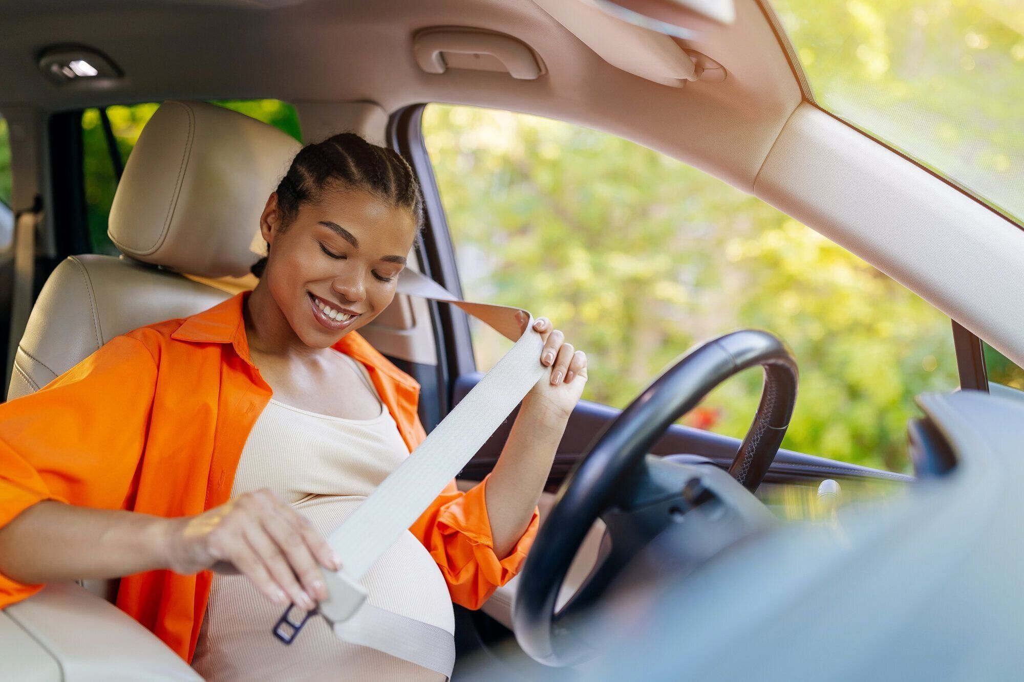 妊娠中の女性が運転席に座りシートベルトを準備している様子