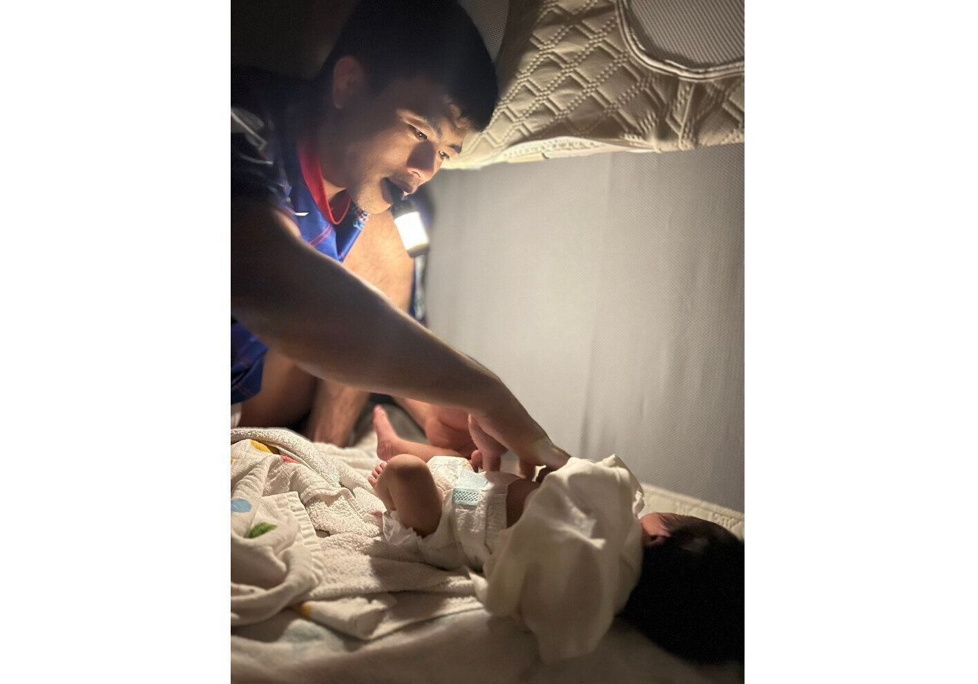 口にライトをくわえながら、夜のおむつ替えをする文田さん。