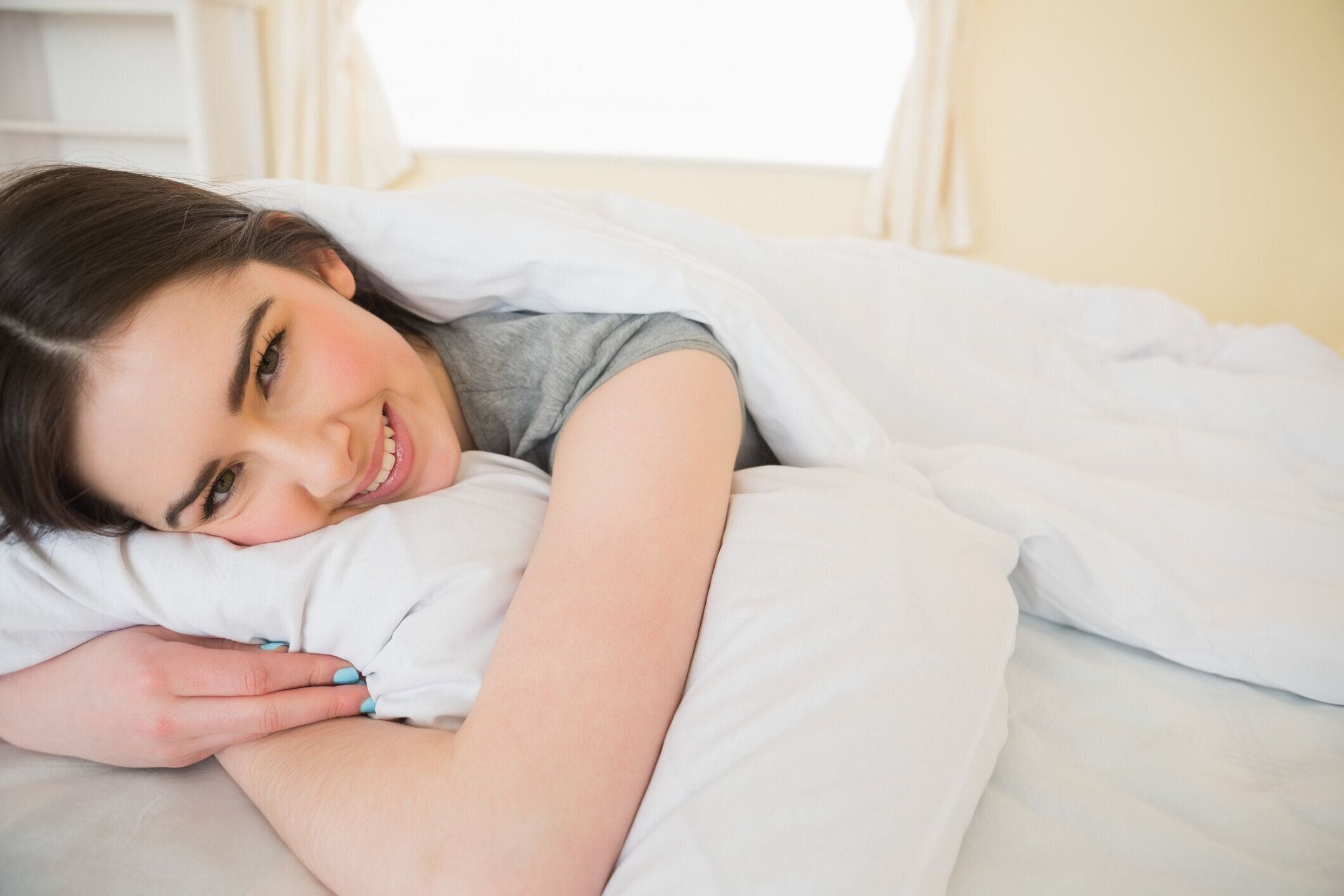 ハッピーなブルネットはベッドでリラックス。