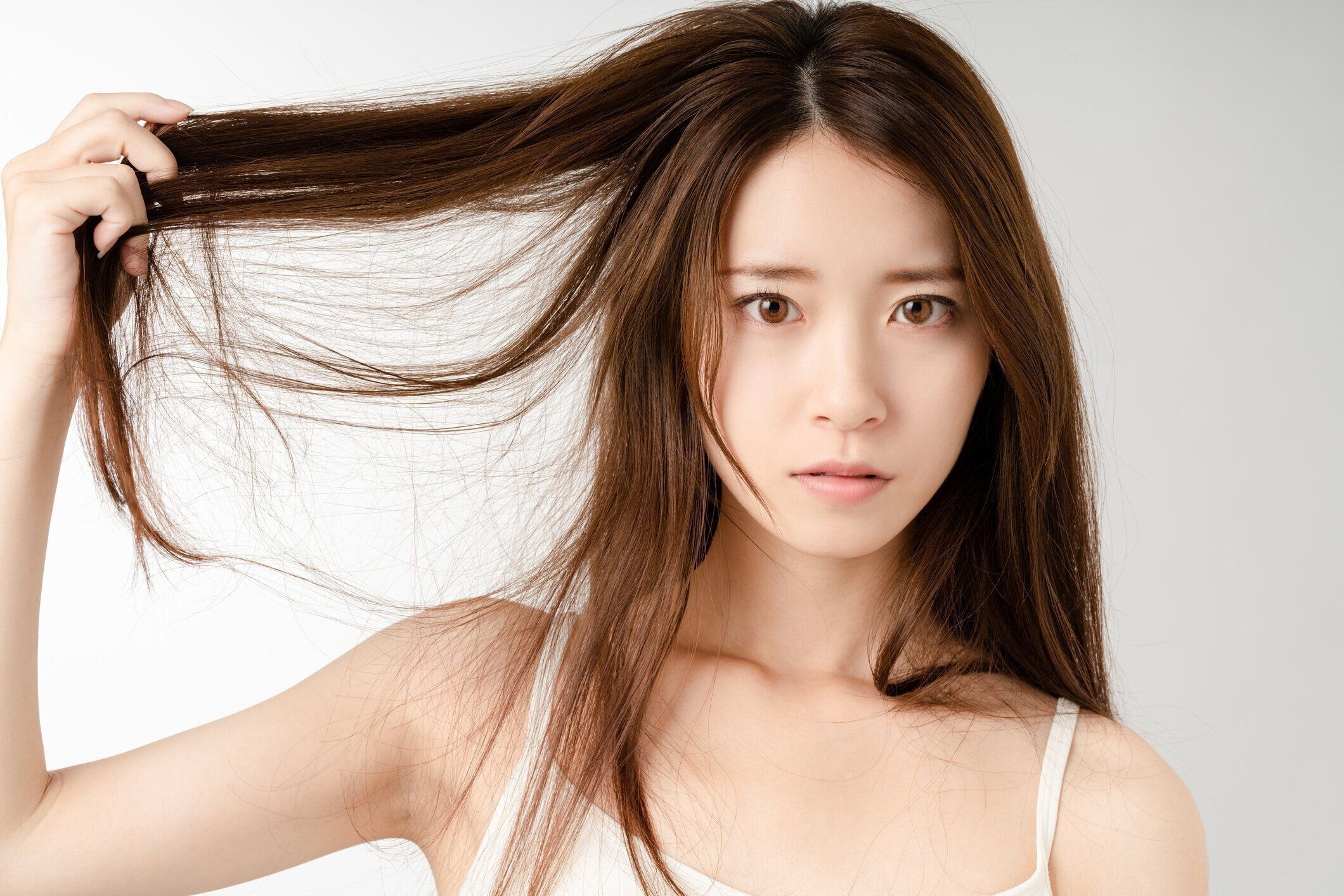 分裂に悩まされる若い女性は終わる。損傷した髪。美容とヘアケアのコンセプト。