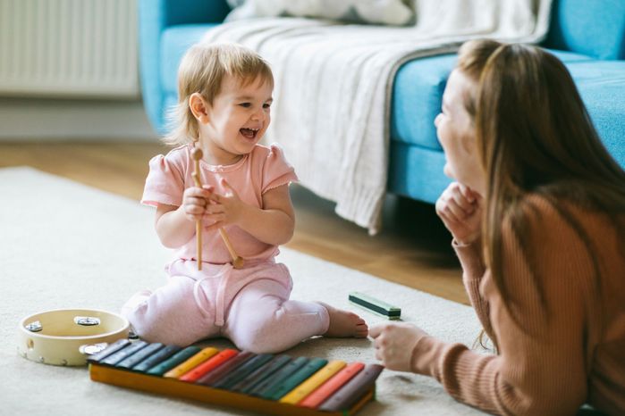 母と1歳半の女の子が楽器を演奏:キシロフォン、ハーモニカ、タンバリン。子どもの初期の音楽教育