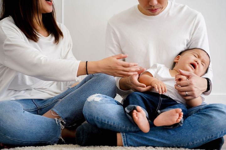 注意のために泣いているアジアの空腹の少年は、彼を慰めようとしている両親を怒鳴ります。アジアのコンセプトにおける親