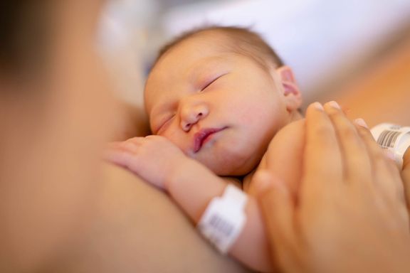 生まれたばかりの赤ちゃんを胸に抱きしめ、皮膚の時間に皮膚を持つママ。病院での出産。