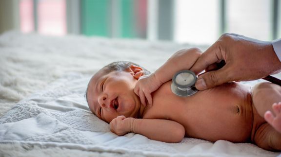医師の手の柔らかいぼかしは、新生児の健康をチェックし、彼の世話をしたり、病気や障害を治すために聴診器を使用しています