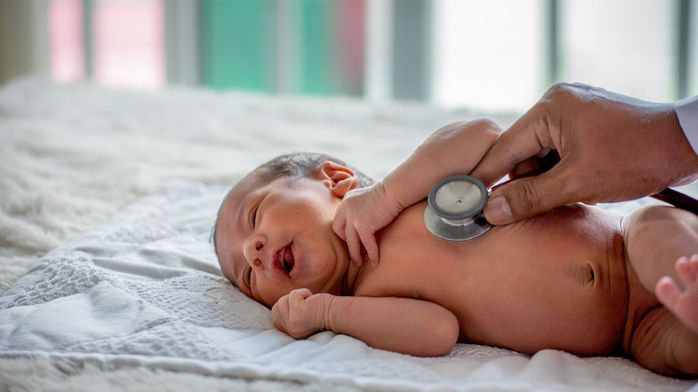医師の手の柔らかいぼかしは、新生児の健康をチェックし、彼の世話をしたり、病気や障害を治すために聴診器を使用しています