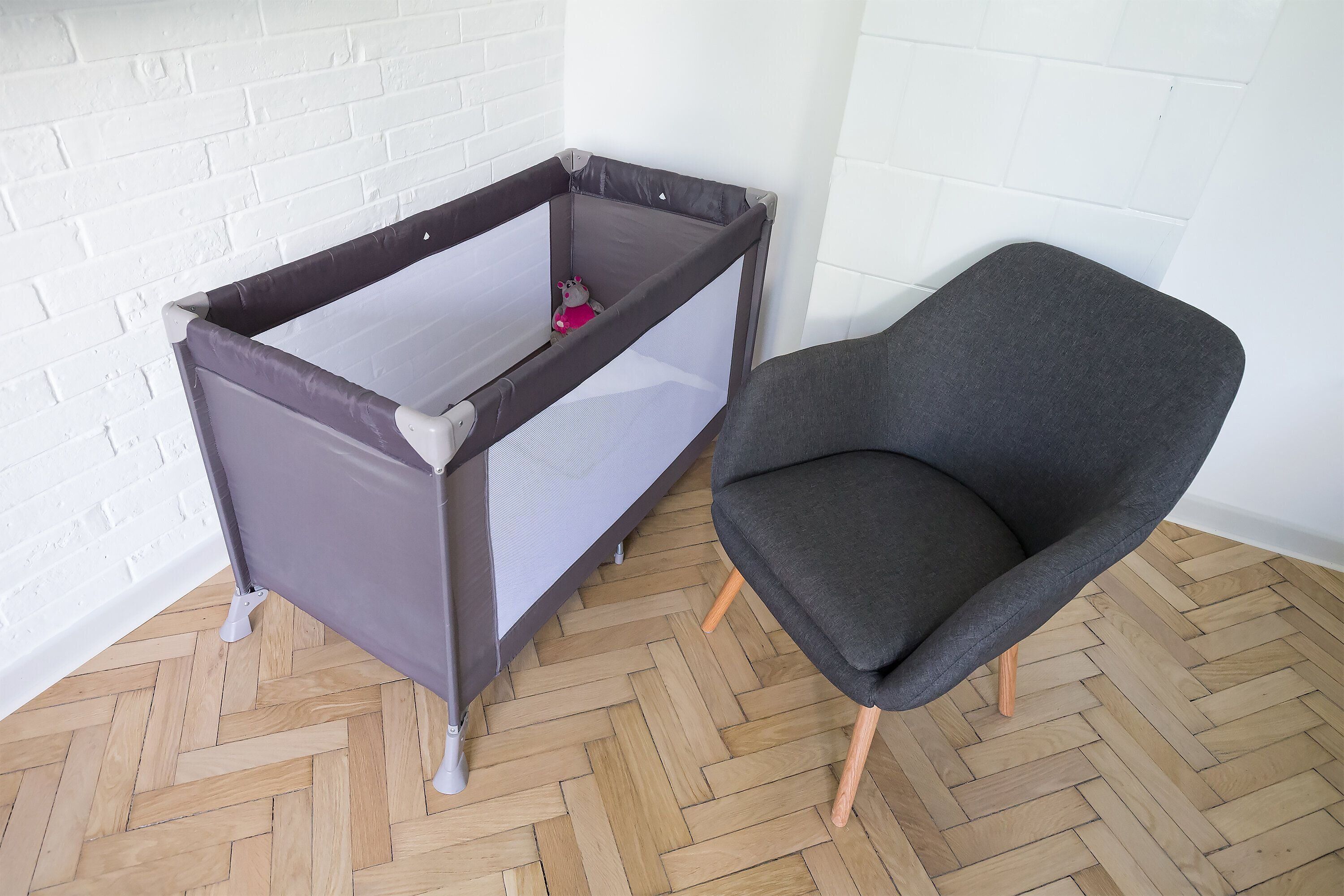 ベビーベッドベッド、グレーと茶色の椅子が備わります