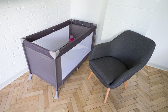 ベビーベッドベッド、グレーと茶色の椅子が備わります