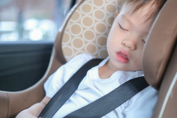 アジア2-3年幼児男の子は、現代の車の座席で眠っています。道路上の安全を旅行する子供