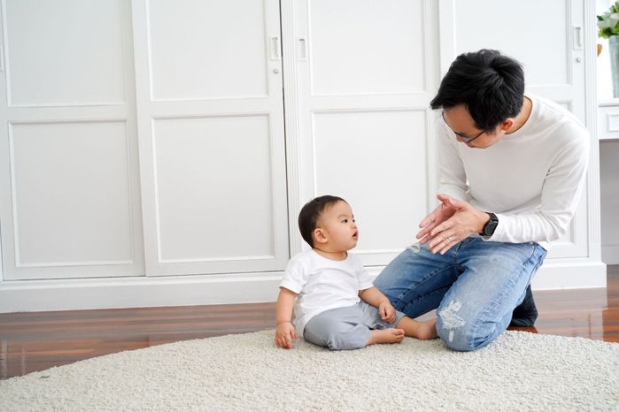 自宅で男の子の子供とゲームや拍手の若い父親の幸せなアジアの家族