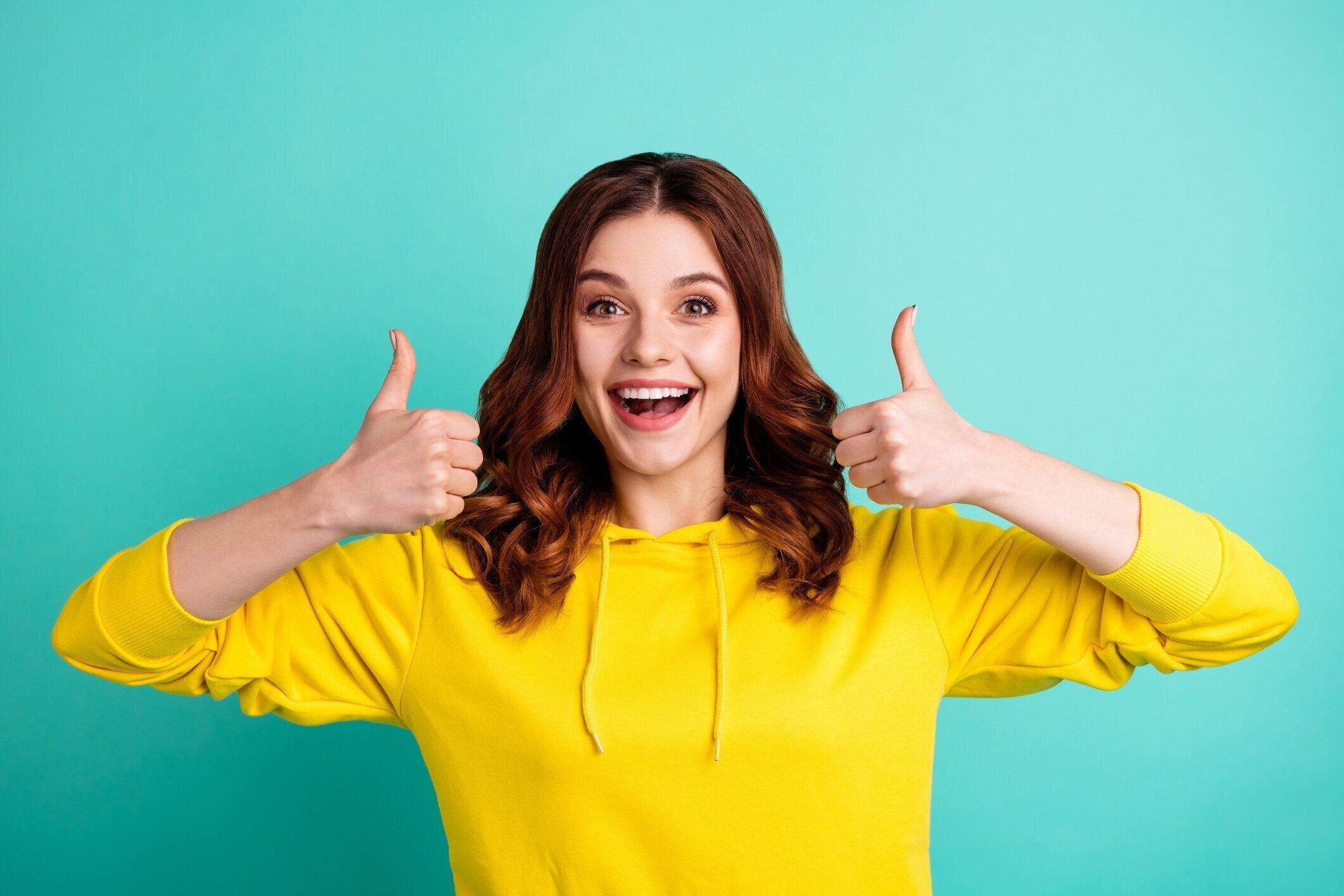 波状のカーリー陽気な陽気な興奮した感情的なガールフレンドの写真は、ターコイズ色の鮮やかな色の背景の上に孤立した二重笑顔を見せています