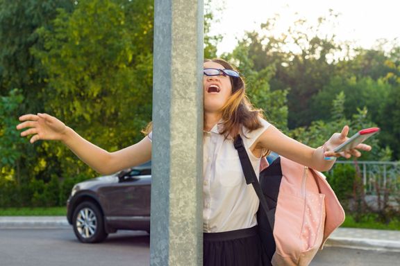 若い無愛想な女の子、携帯電話に気を取られての肖像画。女の子は、通りのポストに墜落した、携帯電話を落としています。