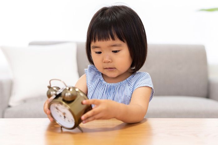 目覚まし時計を持っている小さな女の子