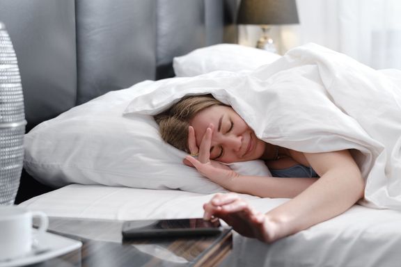 朝ベッドで毛布に覆われた女性