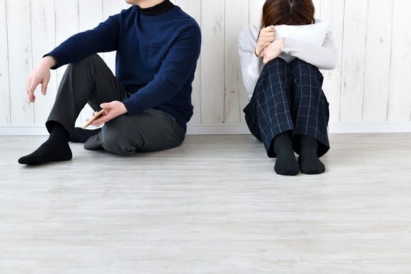 外を見ている男性とリビングルームで泣いている女性
