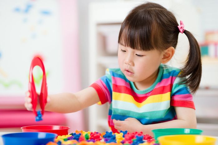 若い女の子は、ホームスクーリングのための細かい運動スキルゲームを選別数学と色を再生します