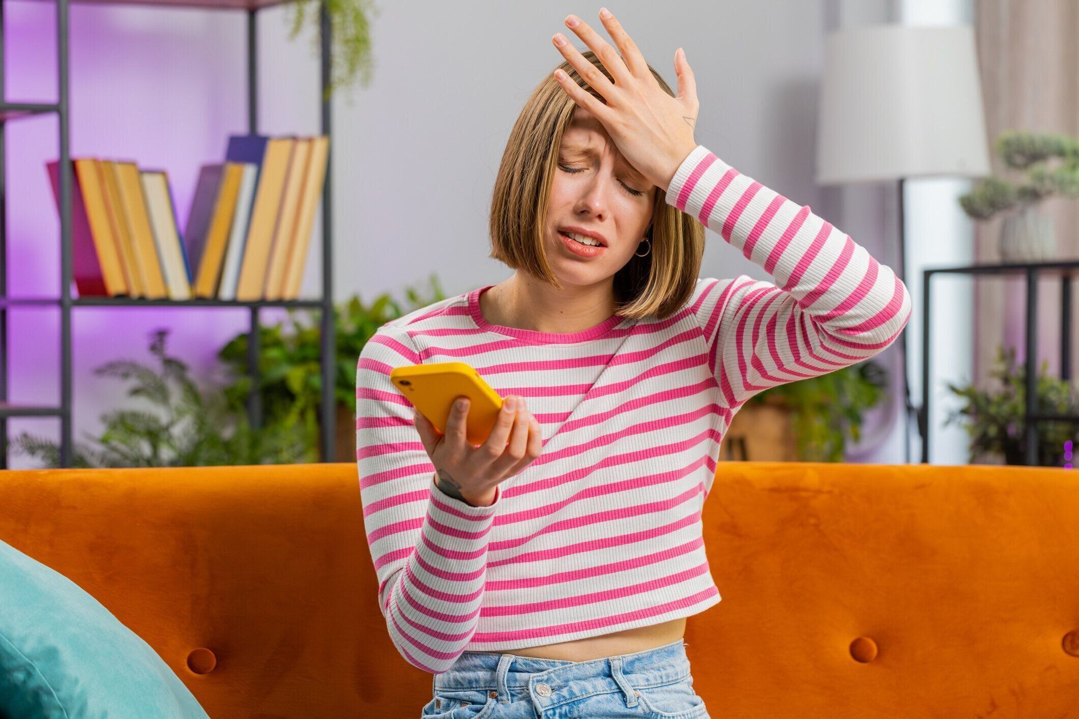 悲しい若い女性は、悪いニュース、財産の損失、失敗、宝くじの結果、締め切りに驚いたスマートフォンを使う