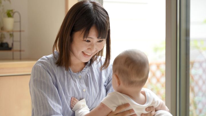 赤ん坊を抱くアジアの若い母親