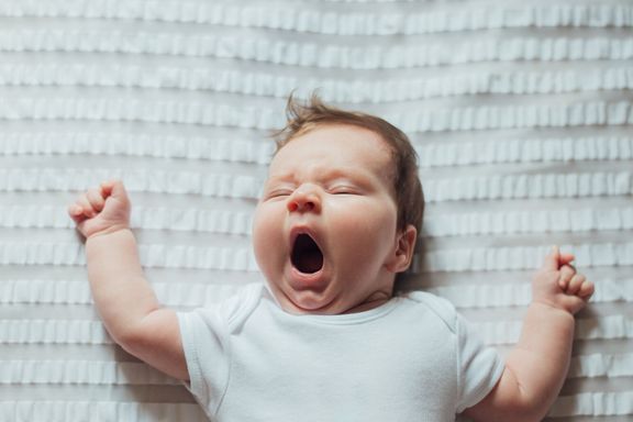 赤ちゃんの睡眠と白いシーツのあくび