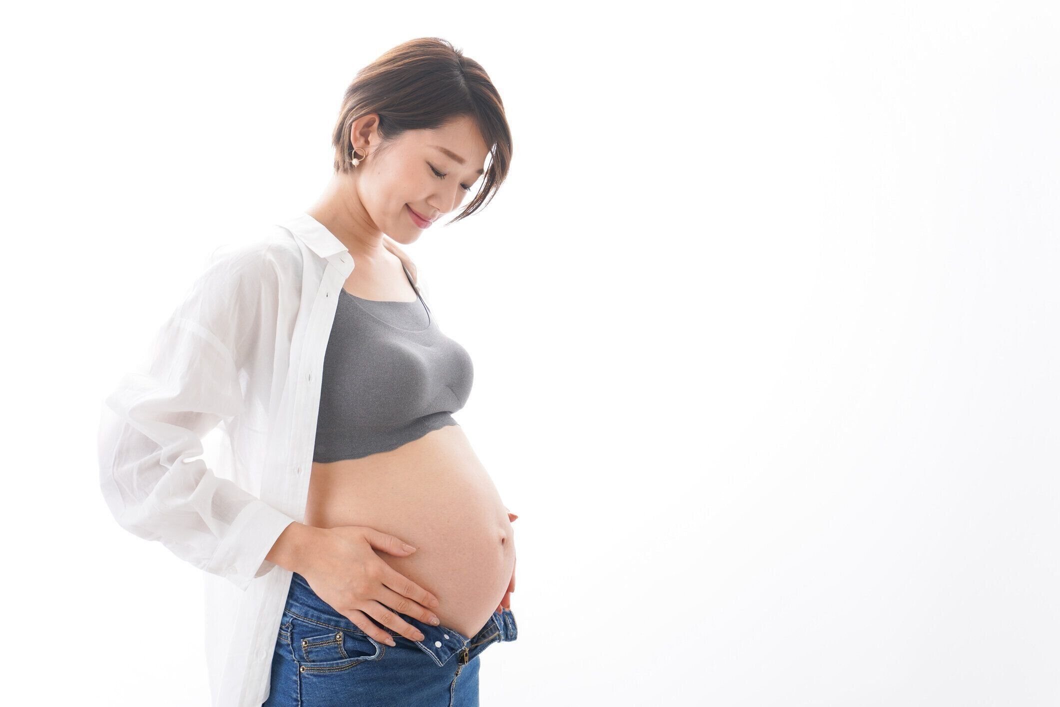 若い妊婦カジュアルウェアで微笑む