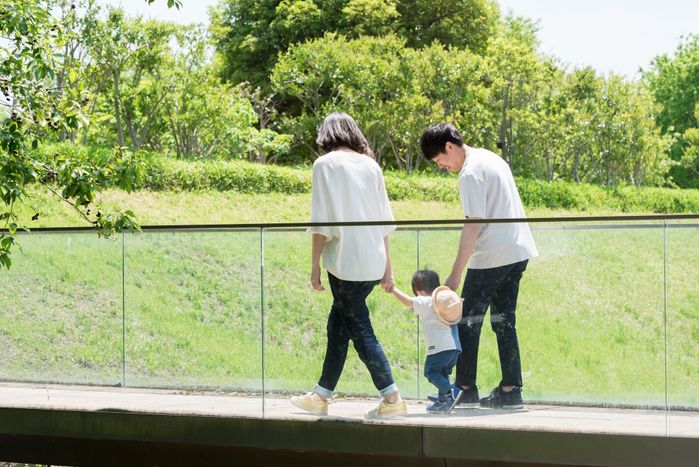 手をつないで歩く3人のアジアの若い家族