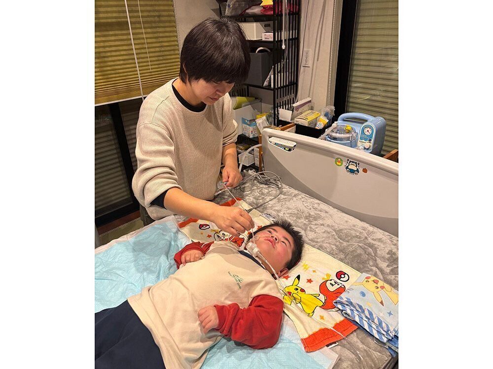 自宅で康介くんをケアする晃子さん　医療的ケア