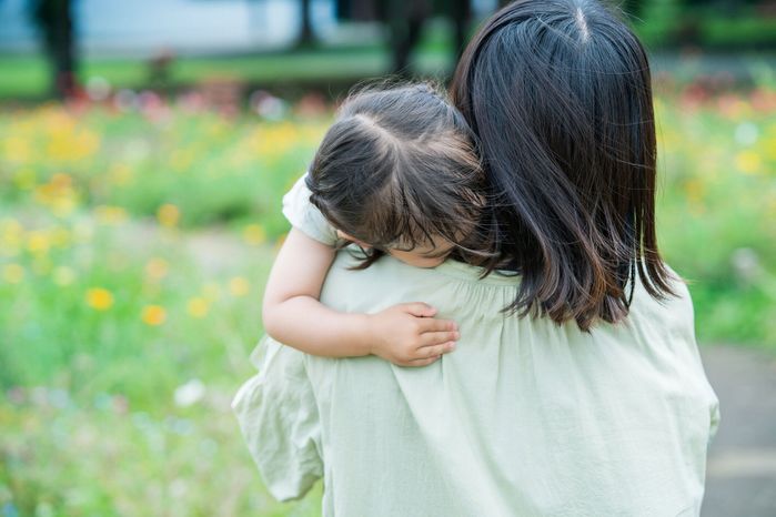 疲れて母親に抱きしめられている少女