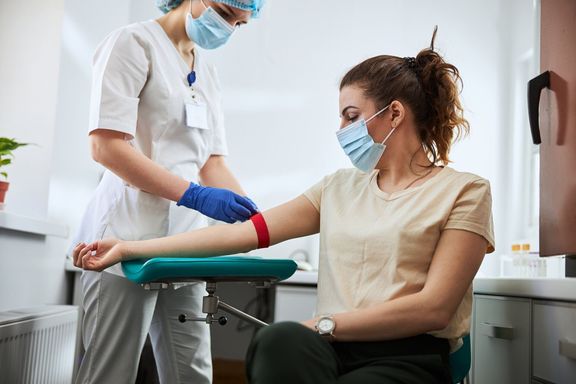 血の引き出しのために女性を準備する経験豊富なフレボトミスト