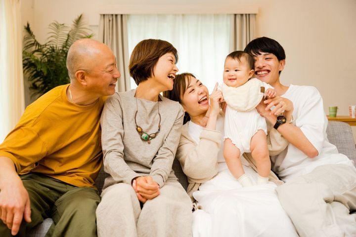 居間で0歳の赤ちゃんを見守る両親と祖父母の3代目の5家族