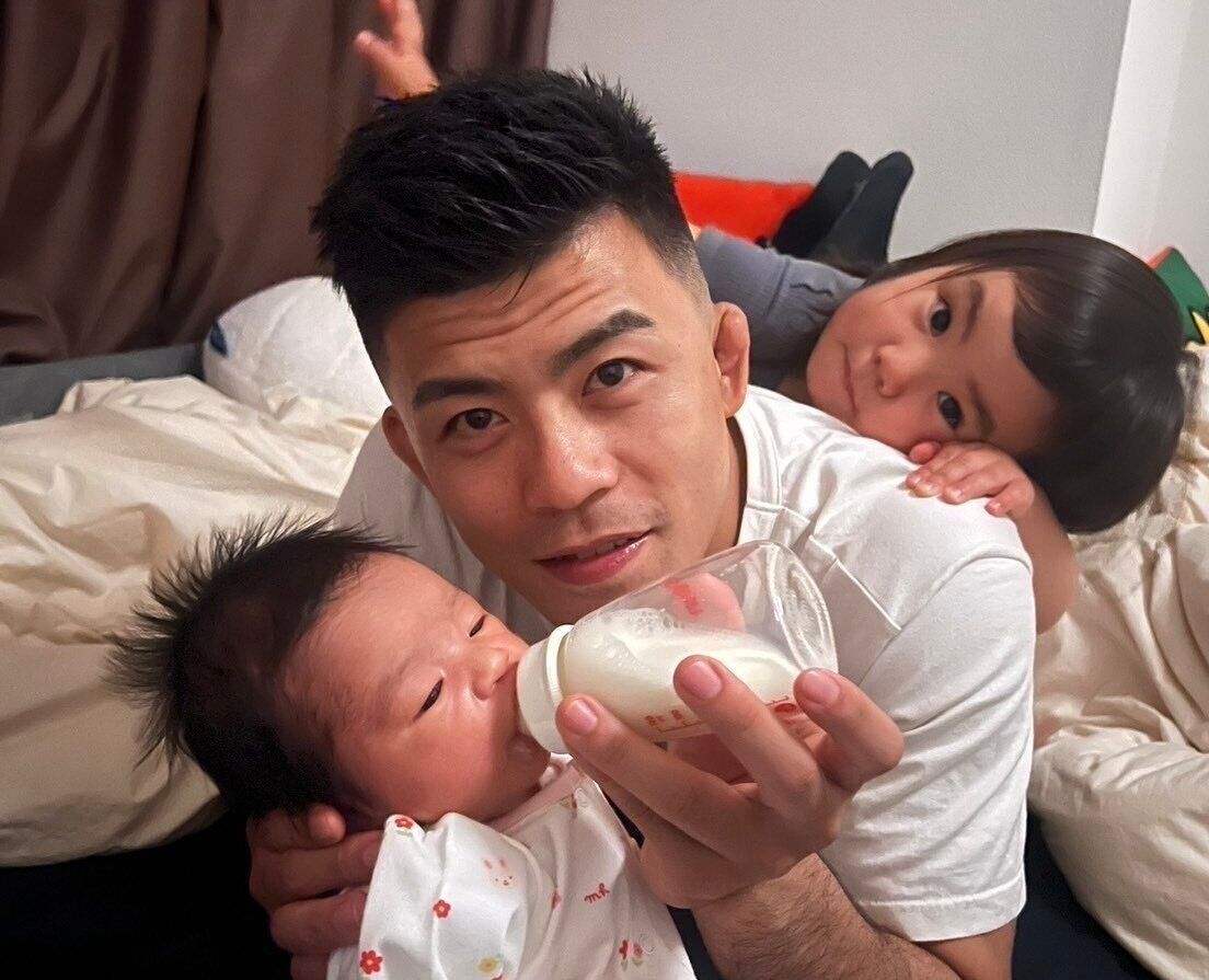 文田さんが二女にミルクをあげる1枚。後ろには、元気な長女。