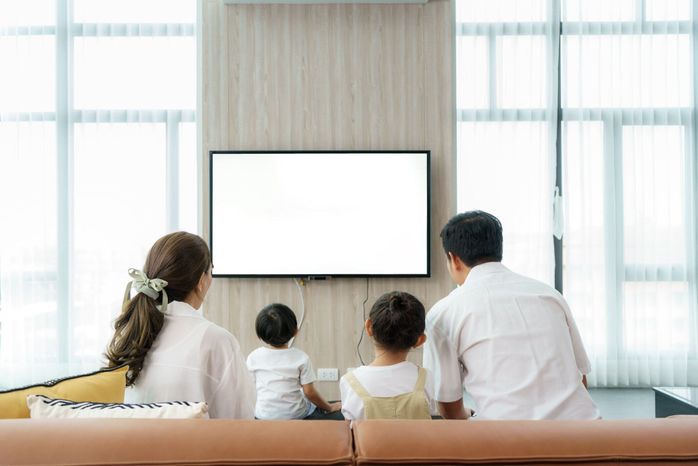 アジアの幸せな家族は自宅のリビングルームで座ってテレビを見て、休暇、休日、幸福やライフスタイルの概念での活動のために一緒に質の高い時間を過ごしました。