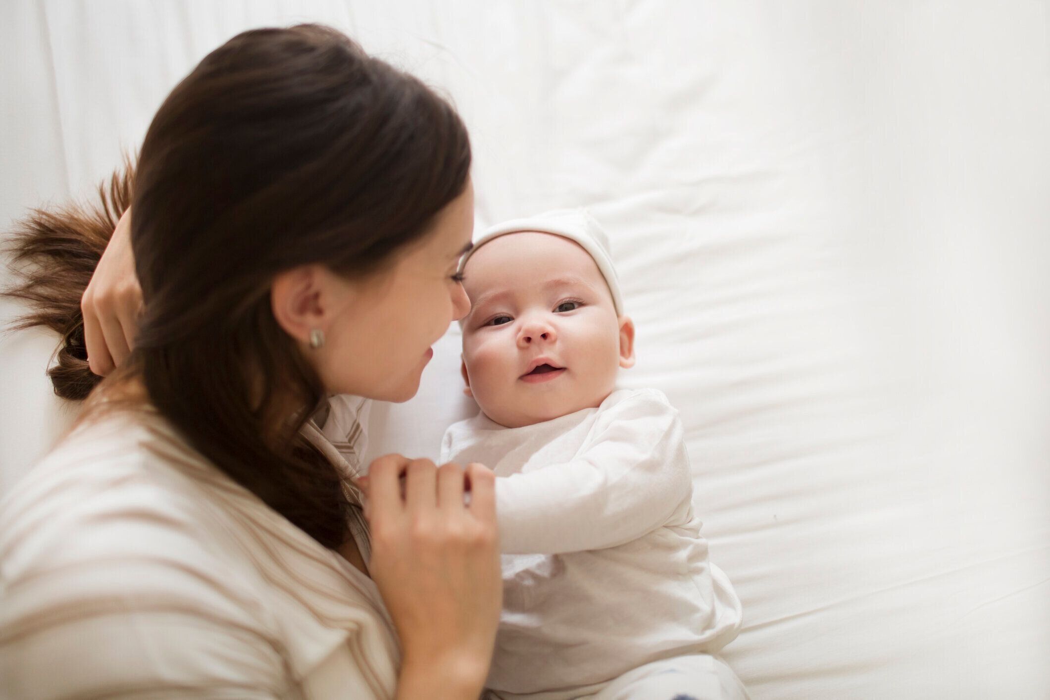 幸せな母と赤ちゃんの子供が一緒にベッドに横たわっている