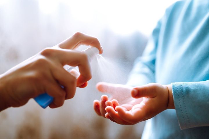 手コロナウイルス保護のために消毒剤を使用する母子。